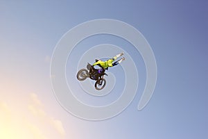 A stunt biker performs a trick in the sky