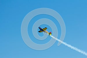 Stunt plane flying against clear blue sky.