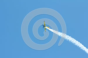 Stunt plane flying against clear blue sky.