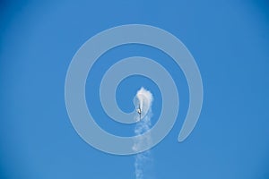 Stunt plane spouting smoke looping and flying sideways in blue sky - Copy space