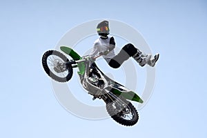 stunt racer in protective uniform and helmet does a dangerous stunt in the air on a motorcycle