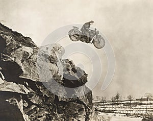 Stuntman on motorbike flying over cliff