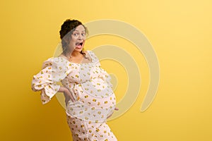 Stupefied pregnant woman holding belly, crying and shouting looking at camera. Easy delivery, pregnancy and parturition