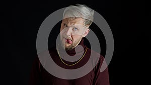 Stupid comical stylish man making funny silly face grimace, playing fool, showing tongue, brainless photo