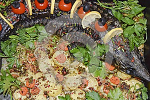 Sturgeon in a baking dish garnished with cherry tomatoes olives and herbs festive dish