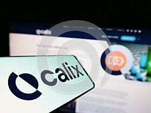 Mobile phone with logo of Australian technology company Calix Limited on screen in front of business website.
