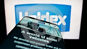 Mobile phone with website of automotive company Haldex Europe SAS on screen in front of business logo.