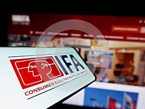 Smartphone with logo of Internationale Funkausstellung Berlin (IFA) on screen in front of business website.