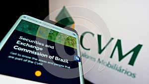 Smartphone with webpage of Brazilian Comissao de Valores Mobiliarios (CVM) on screen in front of logo.