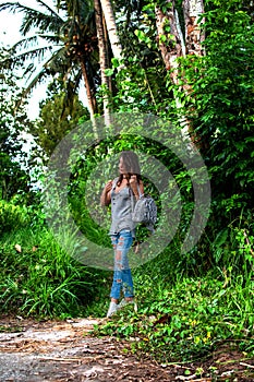 Style girl walking with small bag in jungle. Concept of style, fashion in adventure and travel with python accessory
