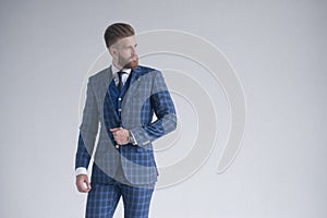 Style in motion. Handsome young man in three-piece suit. posing in front of grey background