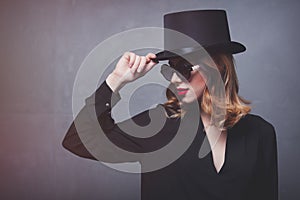 Style and mystique redhead girl in top hat and sunglasses