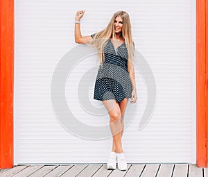 Style portrait of blonde woman outdoor posing in summer. Fashion swag dressed in short dress and Fashion sneakers . Passion s