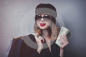 Style redhead girl in hat with shopping bags and money