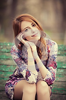 Style redhead girl sitting on the bench