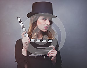 Style redhead girl in top hat with movie clapperboard