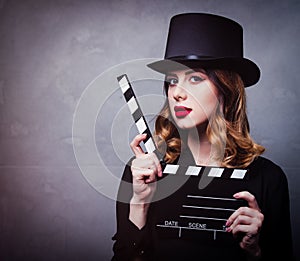 Style redhead girl in top hat with movie clapperboard