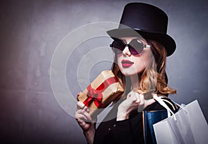 Style redhead girl in top hat with shopping bags and gift box