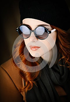 Style redhead woman in sunglasses and coat