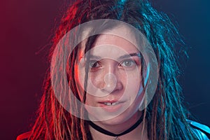 Style, youth, people concept - young cheerful woman with dreadlock looks like rocker over dark background