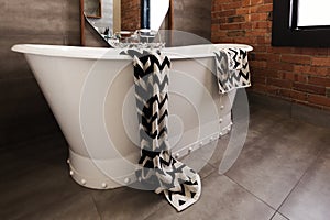 Styled bath towel draped over a freestanding vintage style bath
