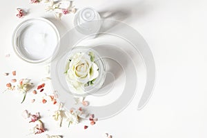 Styled beauty composition. Skin cream, shampoo bottle, dry flowers, rose and Himalayan salt. White table background