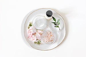 Styled beauty composition. Skin cream, shampoo bottle, rose flowers and Himalayan salt. White table background. Organic