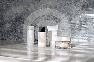 Styled beauty still life, composition Skin cream, shampoo, moisturiser bottles and Himalayan salt in sunny day. White