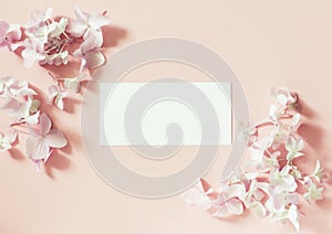 Styled feminine flat lay on pale pastel pink background, top view. Minimal woman`s desktop with blank page mock up, open envelope