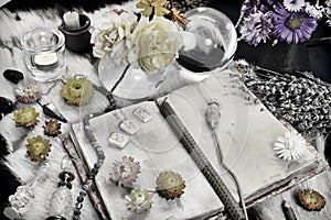 Styled still life with old book, runes, healing herbs and ritual magic objects on witch table