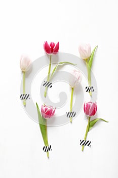 Styled stock photo. Feminine Easter, spring composition with pink tulips taped on white background. Floral pattern. Flat