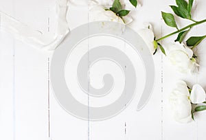 Styled stock photo. Feminine wedding table composition with white peonies flowers and silk ribbon on old white wooden