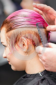 Styling female hair. Male hairdresser makes hairstyle for a young woman in a beauty salon.