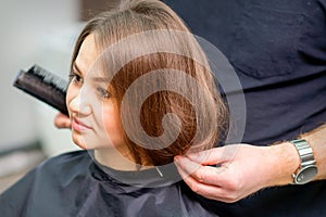 Styling female hair. Male hairdresser makes hairstyle for a young woman in a beauty salon.