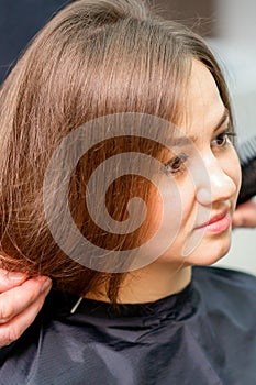 Styling female hair. Male hairdresser makes hairstyle for a young woman in a beauty salon.