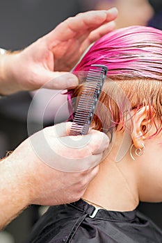 Styling female hair. Male hairdresser makes hairstyle for a young woman in a beauty salon.