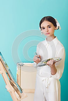 styling teen artist painting on easel with brush and palette
