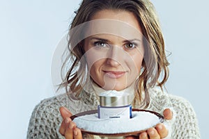 Stylish 40 years old woman showing plate with creme among snow