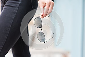 A stylish accessory. Close-up of sunglasses in a woman`s hand. Outdoor