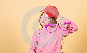 Stylish accessory. Feeling confident with accessories. Girl cute child wear cap or snapback hat hold eyeglasses beige