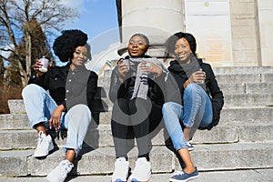 Stylish african american girls drinking coffee on the street