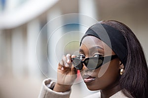 Stylish African American Woman Adjusting Sunglasses Outdoors