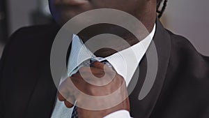 Stylish African Man in a Suit Adjusting the Tie