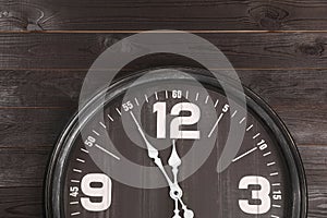 Stylish analog clock hanging on wooden wall. New Year countdown