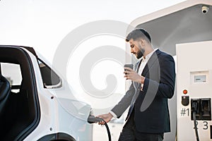 Stylish arabian man charging electric car