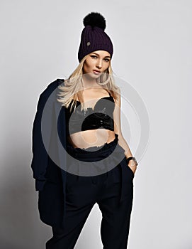 Stylish arrogant woman blonde is posing in plush bralet, blue pants and blue jacket she is holding on her shoulder