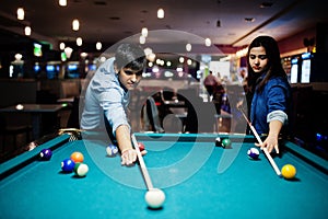 Stylish asian couple wear on jeans playing pool billiard on bar