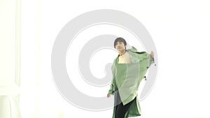 Stylish Asian woman jumping with long overcoat winter fashion on white background Slow motion