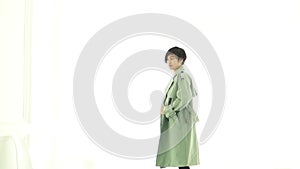 Stylish Asian woman with long green overcoat winter casual fashion on white background Slow motion