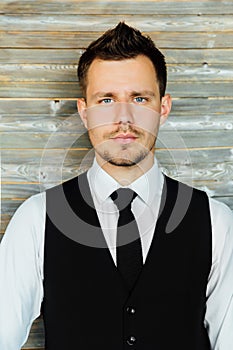 Stylish athletic ofiice man in a business owner costume vest. background of a interior cafe loft.